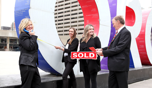 The Simandl Group team celebrating a sold home in front of the RE/MAX sign